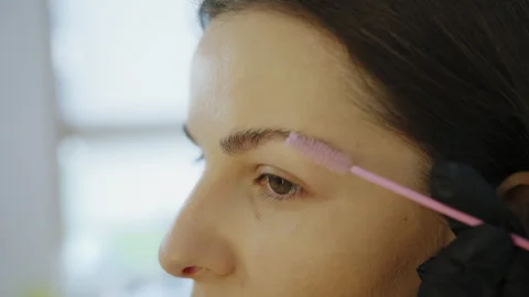 Brushing eyebrows with spoolie during professional brow styling Stock Footage 331825928