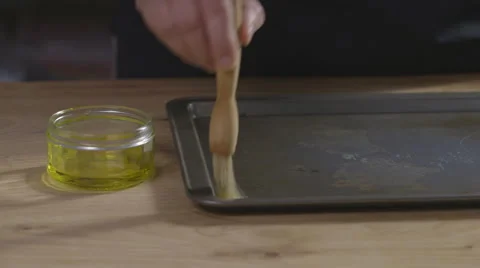 Brushing oil onto a baking tray Stock Footage 64024037
