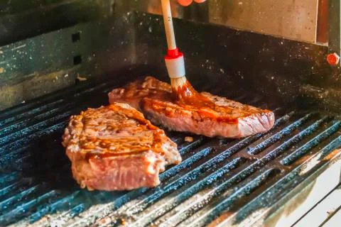 Brushing sauce dip onto bbq beef steaks Stock-Fotos