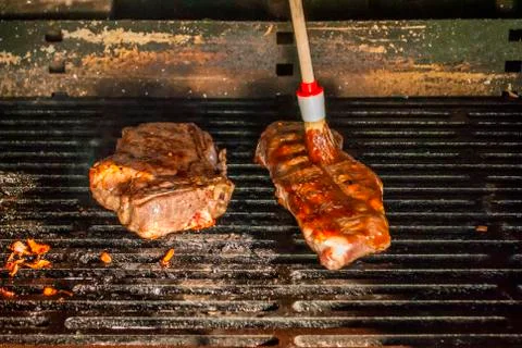Brushing sauce dip onto bbq beef steaks Stock Photos