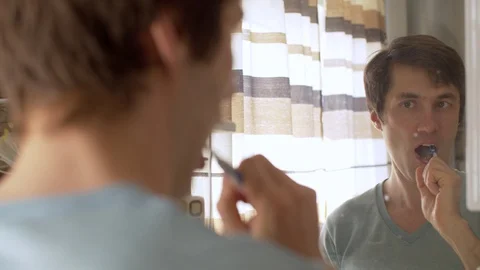 Brushing teeth man reflected in the mirror Stock Footage 128696714