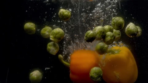 Brussels sprouts and paprika falling into the water with a splash and bubbles Stock Footage 123579252