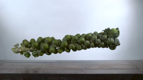 Brussels Sprouts falling in slow motion onto a cutting board - take 2 Stock Footage 64704164