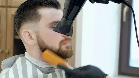 Brutal bearded customer getting his beard cut by a young hairdresser Stock Footage 73545033