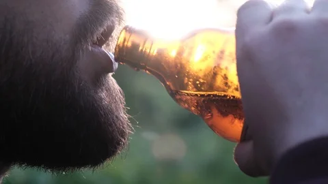 Brutal bearded man drinking beer at sunset slow motion Stock Footage 108061597