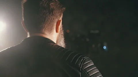 Brutal bearded man in a leather jacket in the dark Stock Footage 89064072