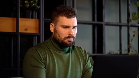 A brutal bearded man is sitting in a cafe and working on a laptop Stock Footage 125660740