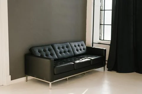 A brutal black sofa in a room with dark gray walls and black curtains on the Stock Photos