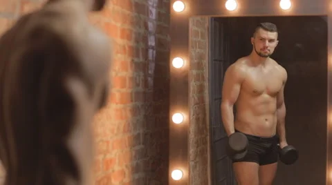 Brutal guy doing curls on biceps in mirror. Ungraded Stock Footage 63301402