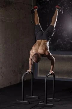 Brutal guy is training on the parallel bars in the sport center Foto stock