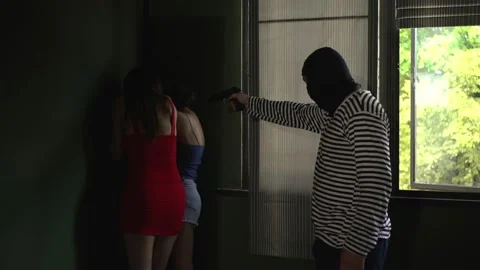 Brutal hooded thief Using a gun to threaten two women at home Stock Footage 222945124