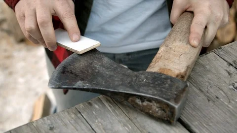 Brutal lumberjack neatly sharpens a blunt ax Stock Footage 123522864