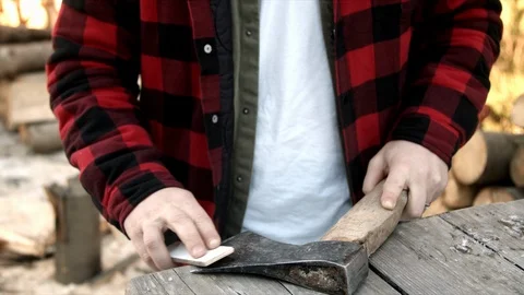 Brutal lumberjack neatly sharpens a blunt ax Stock-Footage 123525659