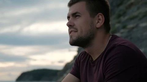 Brutal man with beard smiling on background of rocks at sunset. Video stock 80092401