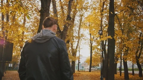 A brutal man in a black leather jacket walks through the autumn forest. Stock Footage 96771148