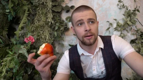 A brutal man picked up a bitten red apple from the floor and is sad, worried Stockbeeldmateriaal 129091662