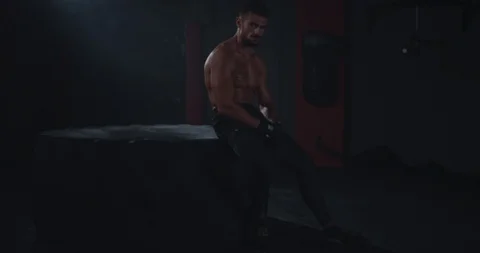 Brutal string fit body guy after his hard workout training sitting in the tire Stock Footage 116901753