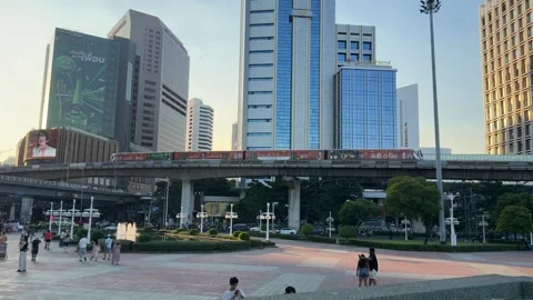 BTS Skytrain passing in front of skyscrapers entrance to Lumphini Park Bangkok Stock Footage 342154995