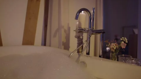Bubble Bath in Bathtub with Candle and Flowers, Home Spa Evening, Close Up Shot Видео 341419741