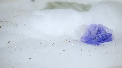 Bubble bath Foam in home Bathtub with soft mesh purple Sponge. Isolated close-up Stock Footage 123606341