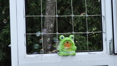 Bubble blower mounted on an open window that blows more bubbles for fun 動画素材 244978234