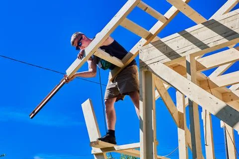 Bubble level helps carpenter check vertical roof framing alignment from tem.. Stock Photos