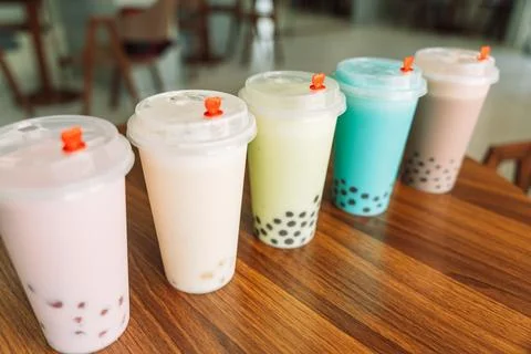 Bubble tea with different flavors in disposable cups with lid on wooden table Stock-Fotos
