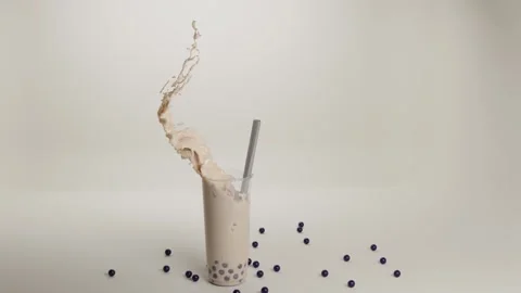 Bubble tea drink glass cup with tapioca or boba, straw, splash and frozen wave Stock Footage 154162558