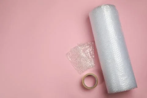 Bubble wrap and tape on light pink background, flat lay. Space for text Stock Photos