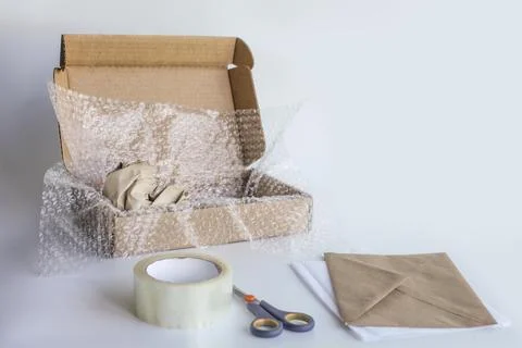 Bubble wrap, box, tape, scissors, paper envelope. Product packaging concept. Stock Photos