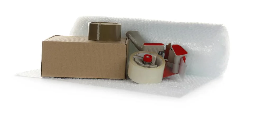 Bubble wrap roll, cardboard box and tape dispenser on white background Stock Photos
