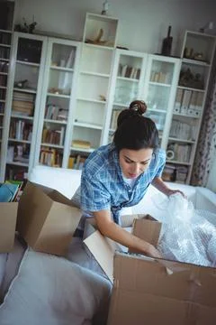 Bubble wrap spilling from open boxes onto sofa in living room beside bookshelf Stock Photos