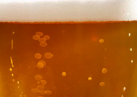 Bubbles and foam in the rays of light in a glass of beer close-up Foto stock