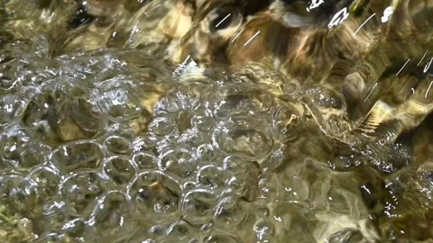 Bubbles and sunlight effects on a mountain river (slow motion) Video stock 212885724