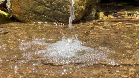 Bubbles ascend gracefully from a forest's petite waterfall Stock Footage 250271392