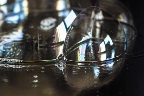 Bubbles on black mirror reflecting a window. Selective focus on the small bub 写真素材