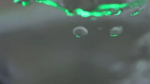 Bubbles in boiling water liquid with green light Video stock 155369580