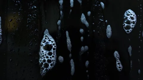 Bubbles create an abstract face shape on a dark surface in a unique artistic Stock Footage 328302876