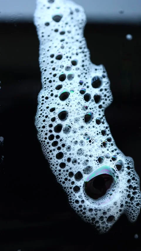 Bubbles create an abstract face shape on a dark surface in a unique artistic Stock Footage 328302969