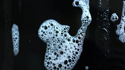 Bubbles create an abstract face shape on a dark surface in a unique artistic Stock Footage 328303331