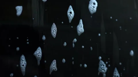 Bubbles create an abstract face shape on a dark surface in a unique artistic Stock Footage 328303711