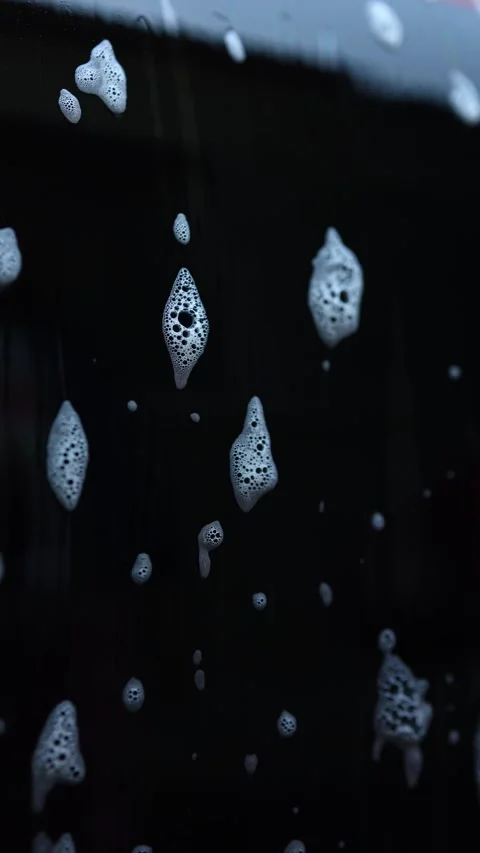 Bubbles create an abstract face shape on a dark surface in a unique artistic Stock Footage 328303744