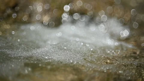 Bubbles created by a waterfall from a mountain stream (slow motion, bokeh) Video stock 219634799