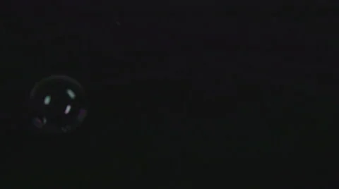 Bubbles fall down on black surface and burst in slow motion Stock Footage 58761275