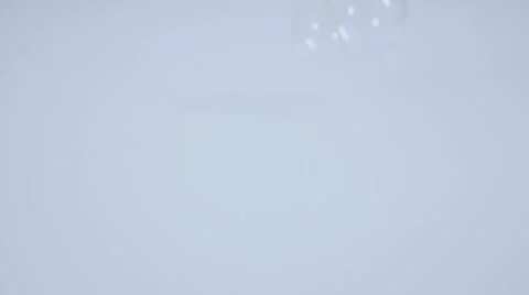 Bubbles fall down on white surface and burst in slow motion Stock Footage 58761219