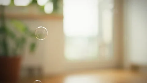 Bubbles float gently in a sunlit indoor space creating a dreamy atmosphere o Stock Footage 323731419