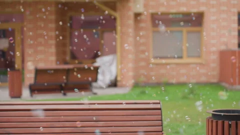 Bubbles Floating Across Courtyard with Bench and Brick Building Vídeos de archivo 321478196