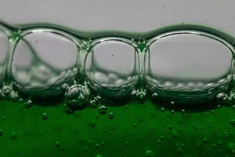 Bubbles form on the surface of a green liquid, creating a mesmerizing abstrac Stock Photos