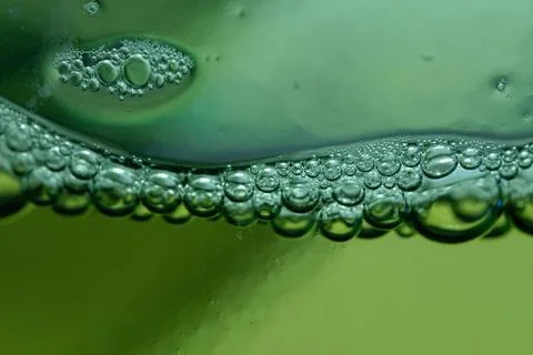 Bubbles form on the surface of a green liquid, creating a mesmerizing abstrac Stock Photos