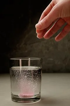 Bubbles form as a tablet dissolves in clear water with a delicate touch Stock Photos